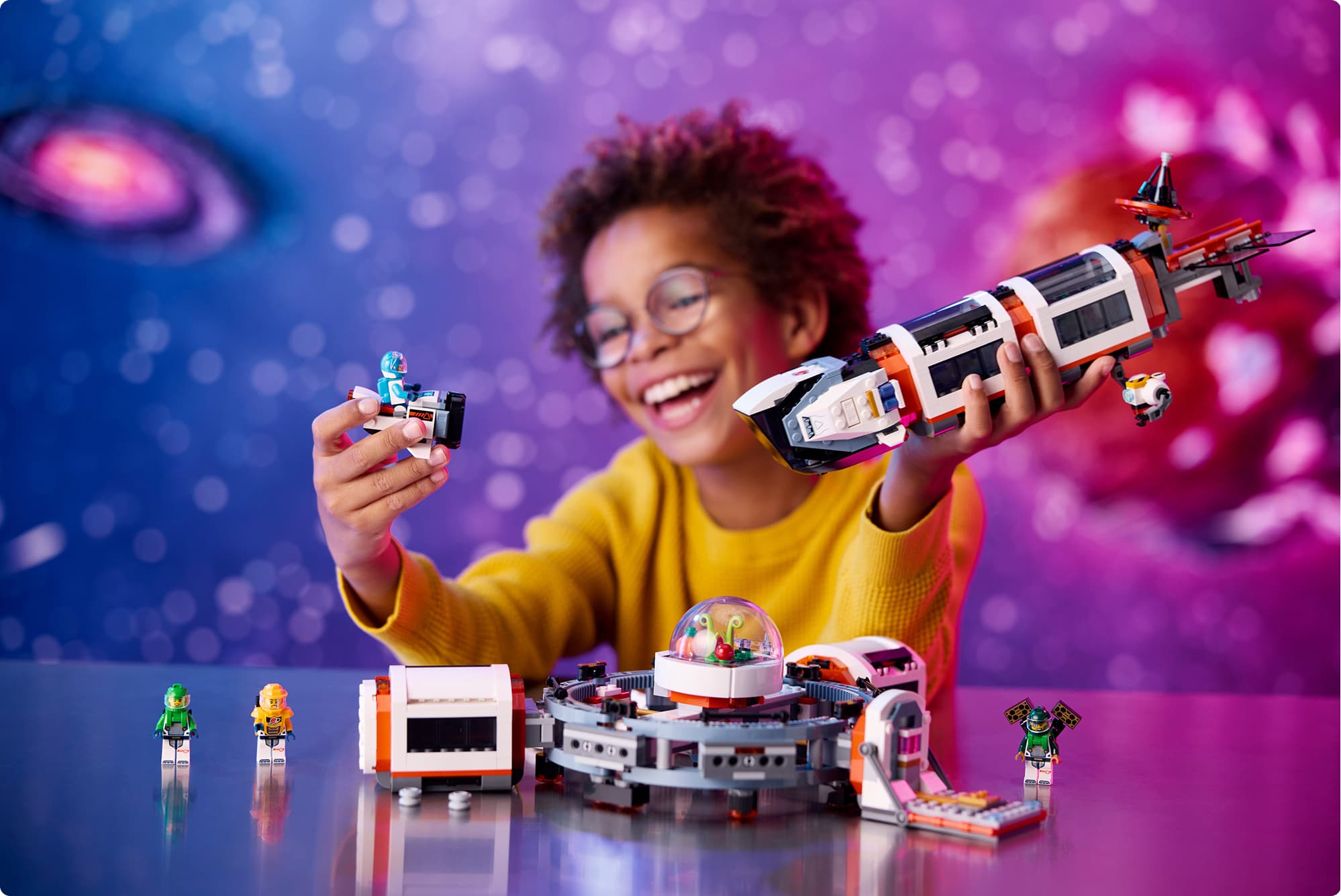 Een leerling houdt lachend een zelfgebouwd ruimteschip van LEGO omhoog.