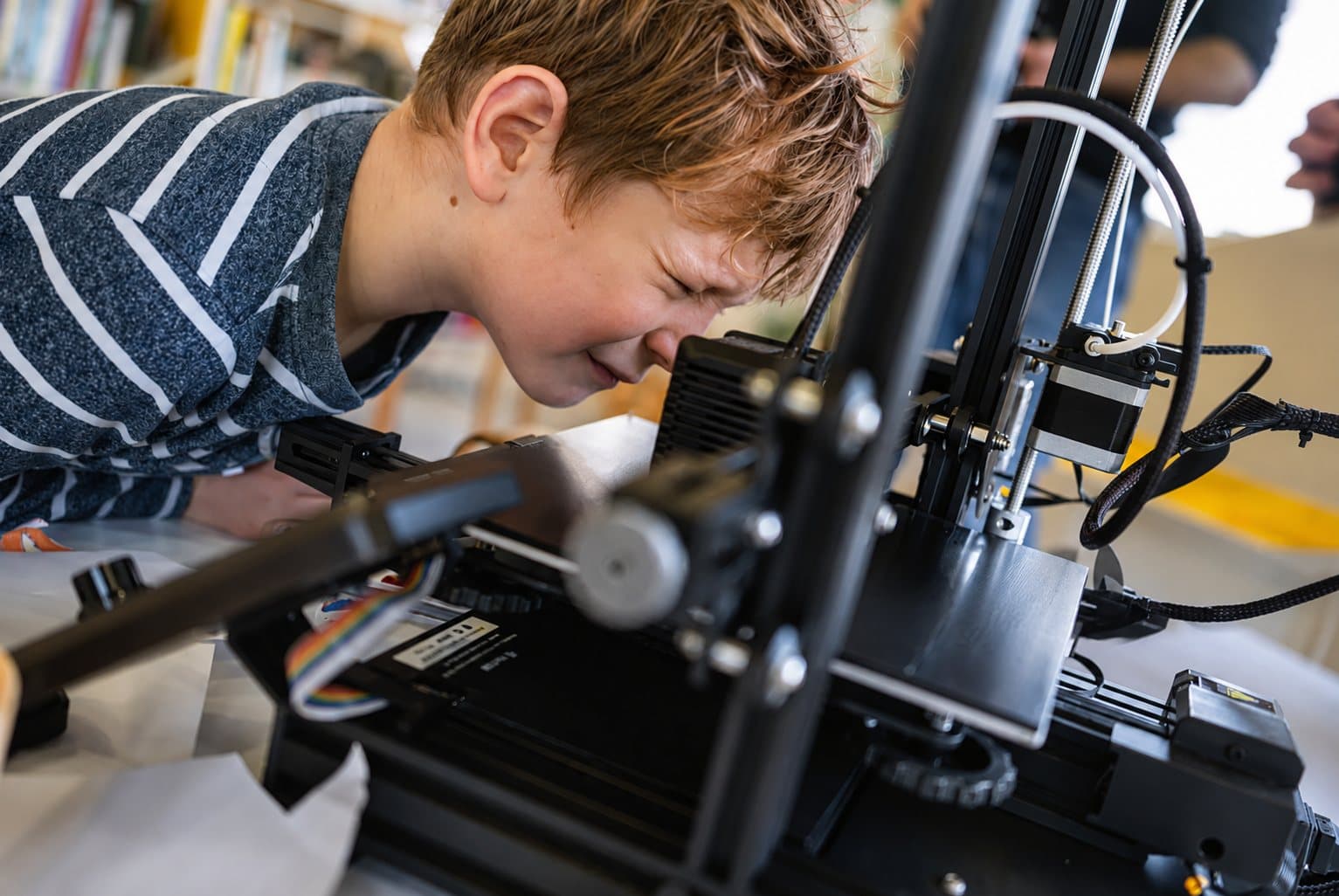 Een leerling kijkt van dichtbij toe hoe de 3D-printer zijn ontwerp print.